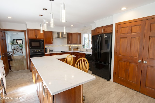 kitchen with black appliances, a sink, a kitchen island, wall chimney exhaust hood, and decorative light fixtures