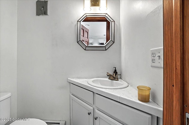 half bath featuring toilet, vanity, and a baseboard radiator