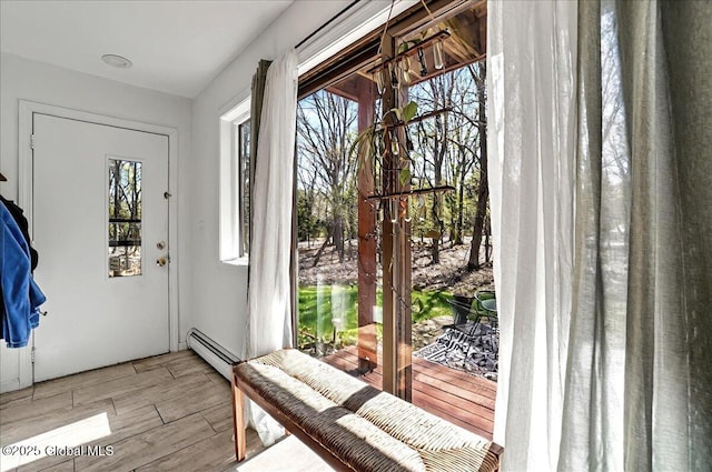 doorway to outside with wood finished floors and a baseboard radiator