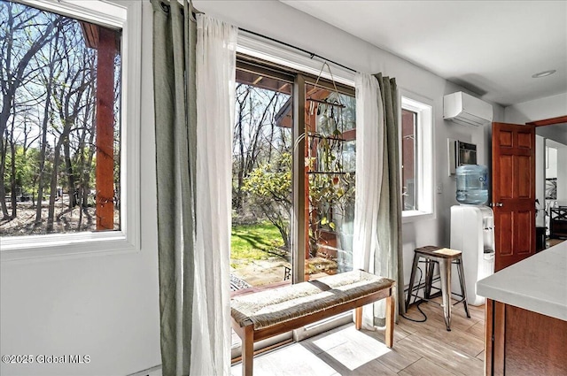 entryway with an AC wall unit, healthy amount of natural light, and light wood-style flooring