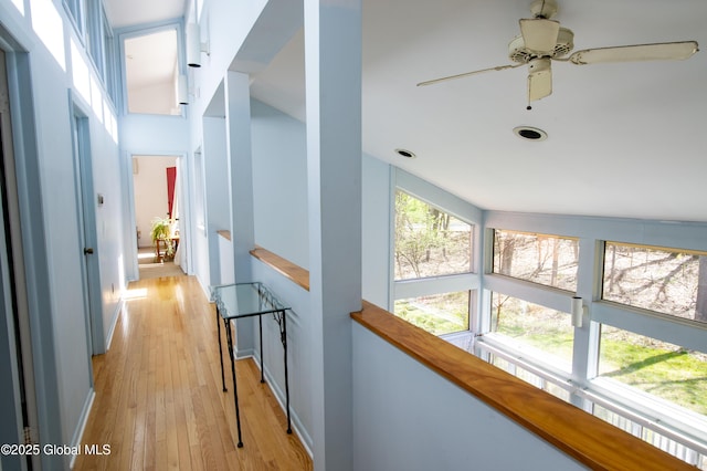 hallway featuring an upstairs landing and light wood-style flooring