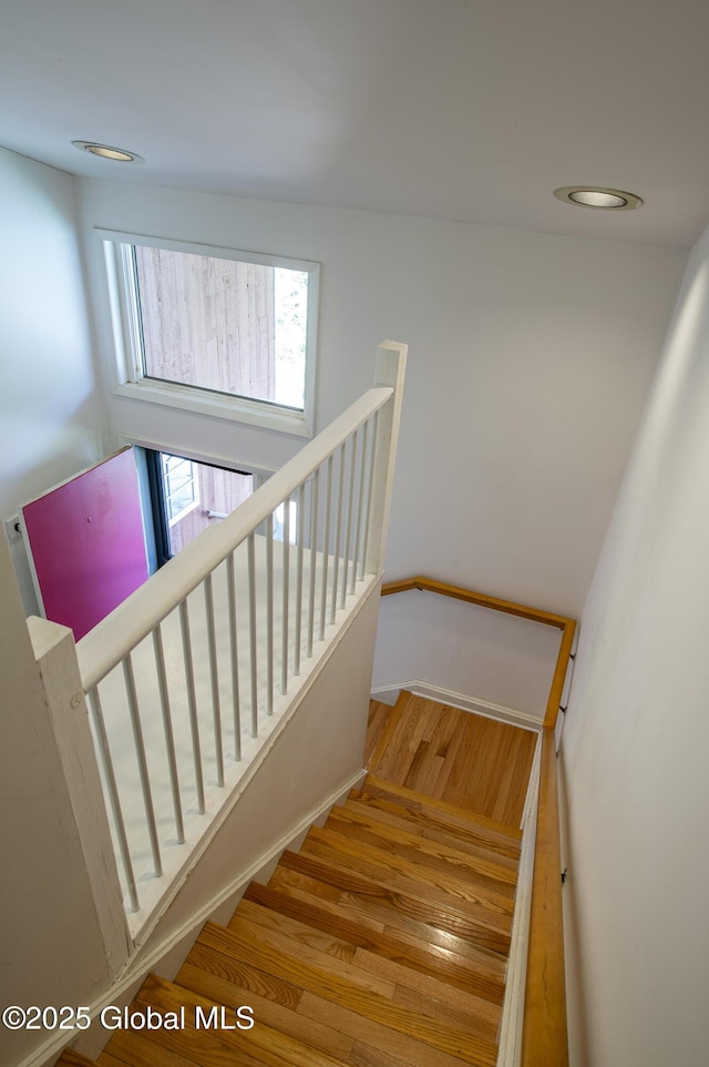 stairs with wood finished floors, baseboards, and recessed lighting