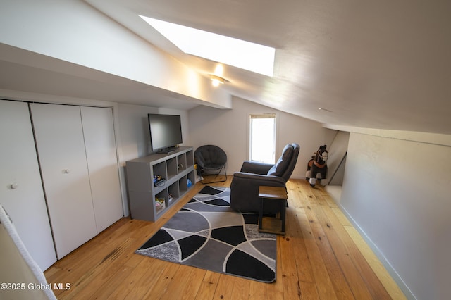 living area featuring a skylight, lofted ceiling, and light wood-style flooring