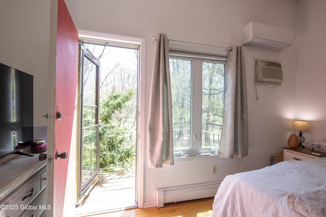 bedroom with a baseboard radiator, a wall mounted AC, access to exterior, a wall unit AC, and light wood-style flooring