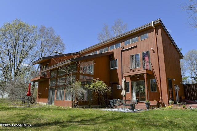 rear view of house featuring a balcony and a yard