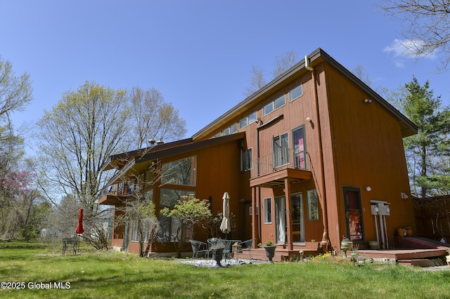back of house featuring a balcony and a yard