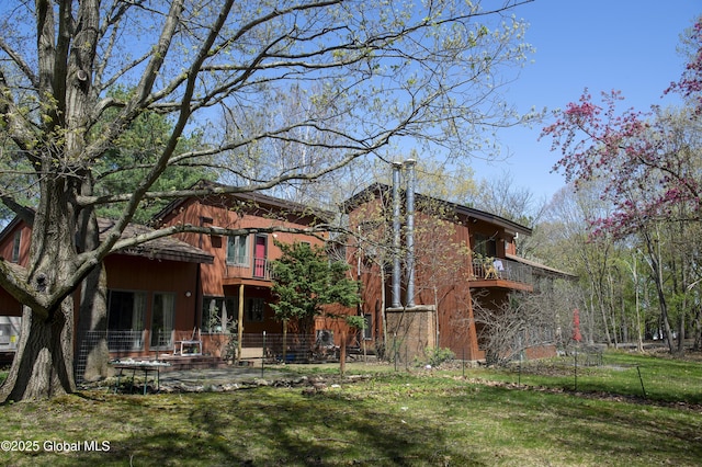 back of house with a balcony and a lawn