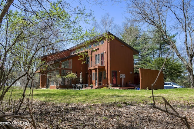 rear view of property with a balcony and a lawn