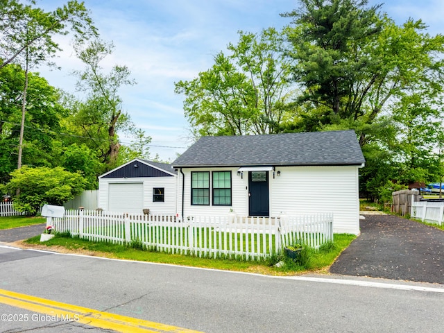15 Schaffer Dr, Colonie, NY 12047 - view of front facade with a detached garage, asphalt driveway, a fenced front yard, and a shingled roof