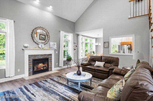 264 Edie Rd, Wilton, NY 12866 - living room with wood finished floors, high vaulted ceiling, a stone fireplace, baseboards, and a chandelier