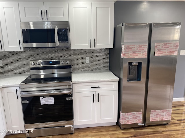 2112 Gray St, Rotterdam, NY 12306 - kitchen featuring appliances with stainless steel finishes, light countertops, white cabinets, wood finished floors, and backsplash