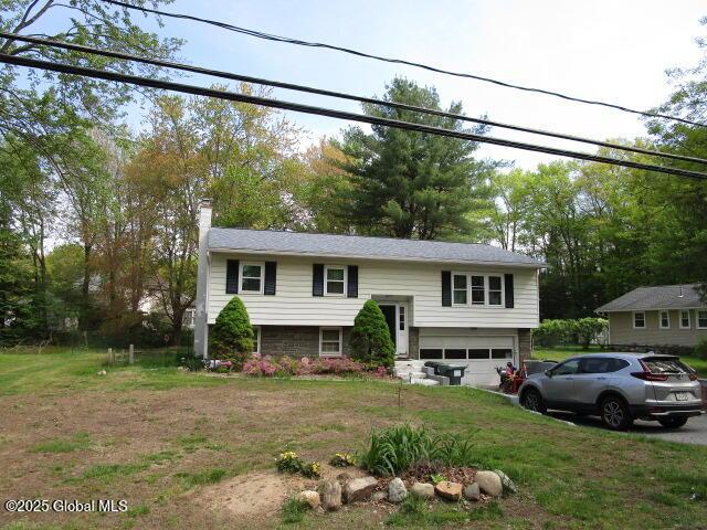bi-level home featuring a garage, a chimney, and a front yard