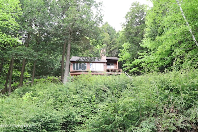 441 E Kelm Pond Rd, Warrensburg, NY 12885 - rear view of house featuring a chimney, a deck, and a forest view