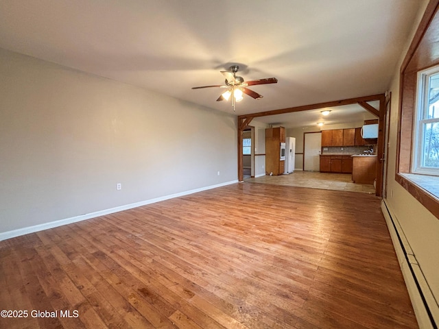 3 Schuyler Ave, Ravena, NY 12143 - unfurnished living room with baseboard heating, light wood-style floors, ceiling fan, and baseboards
