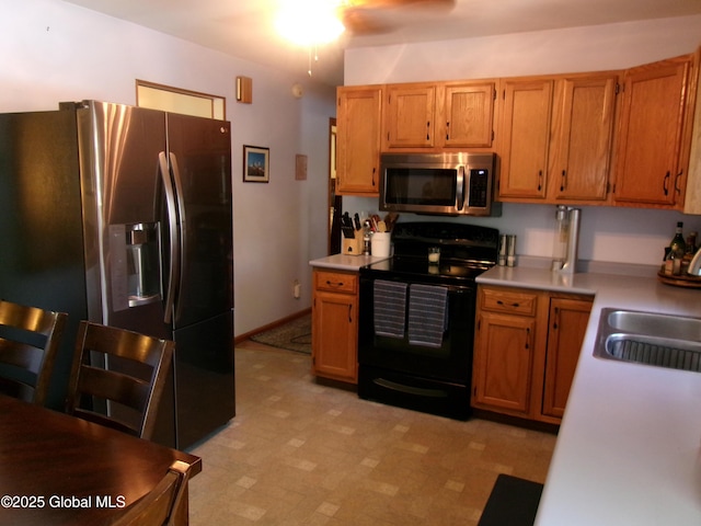 kitchen featuring appliances with stainless steel finishes, light countertops, a sink, light floors, and ceiling fan