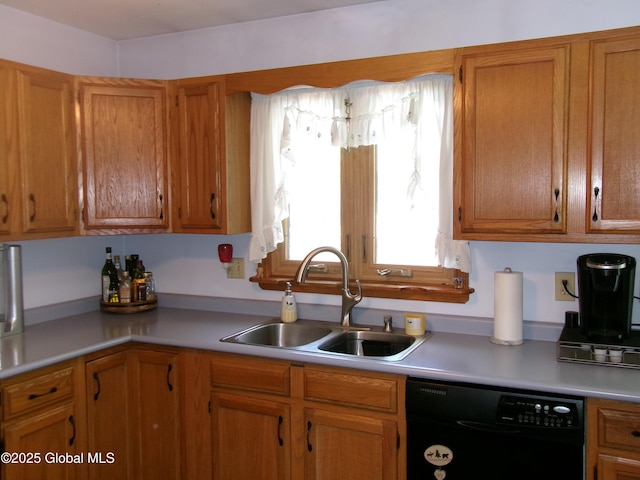 kitchen featuring black dishwasher, a sink, light countertops, and brown cabinetry