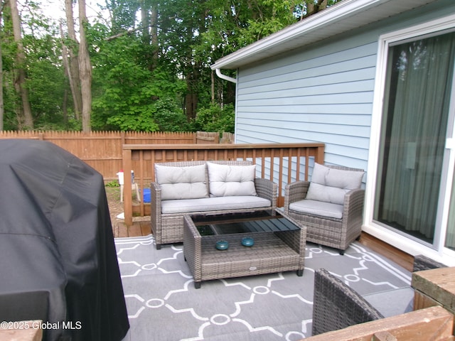 wooden terrace with outdoor lounge area, grilling area, and fence