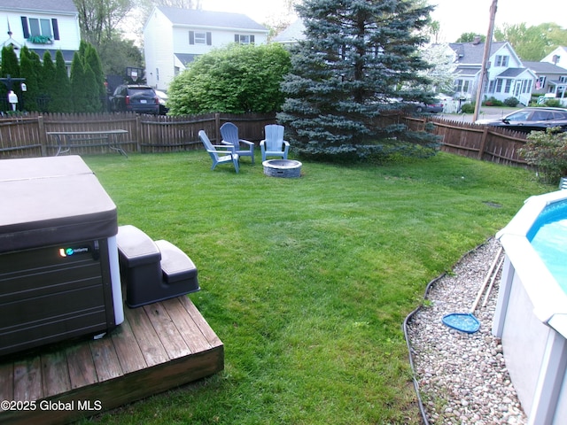 view of yard featuring a hot tub, a residential view, an outdoor fire pit, and a deck