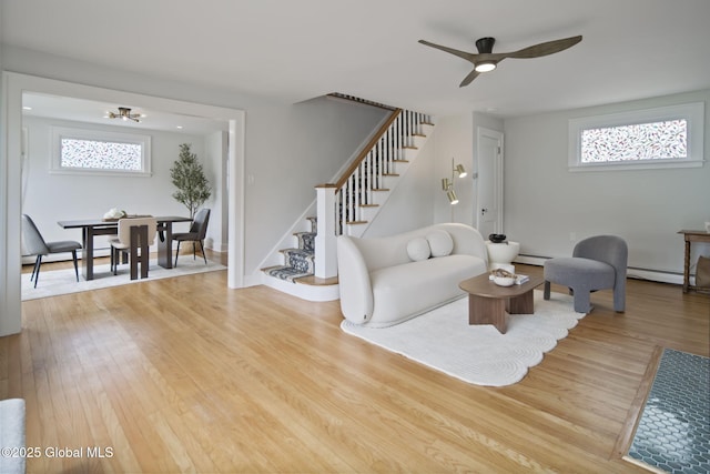 living room featuring stairway, a baseboard heating unit, and healthy amount of natural light