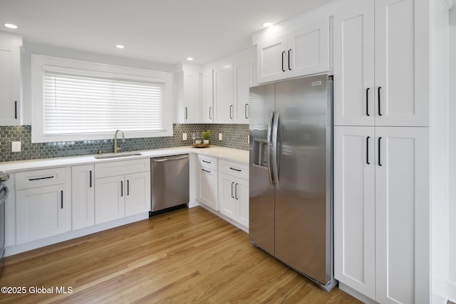 kitchen featuring stainless steel appliances, a sink, white cabinetry, light wood finished floors, and recessed lighting