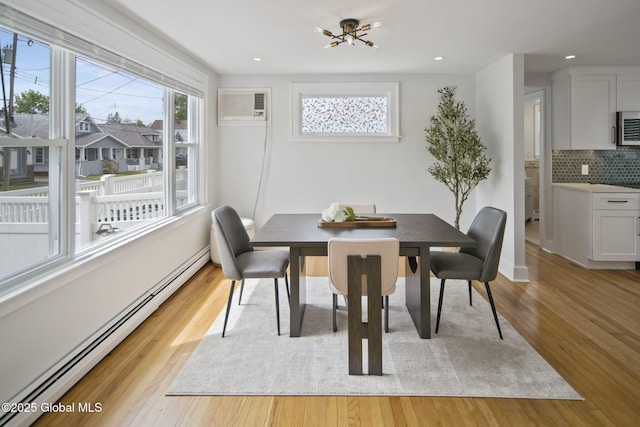 dining space with a baseboard heating unit, a wall mounted air conditioner, light wood finished floors, recessed lighting, and a chandelier