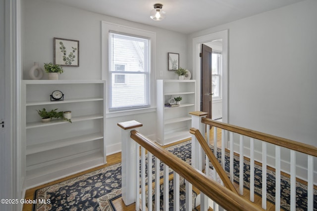 corridor with an upstairs landing and light wood-style flooring