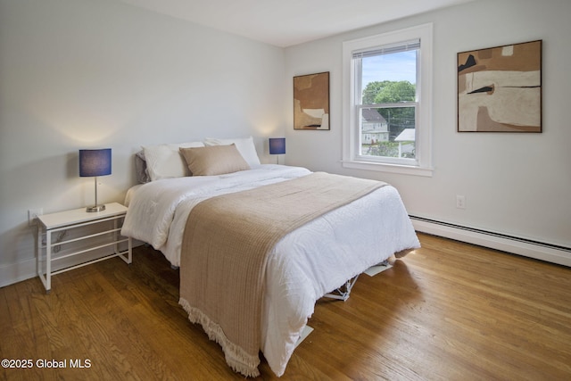 bedroom featuring a baseboard heating unit and wood finished floors