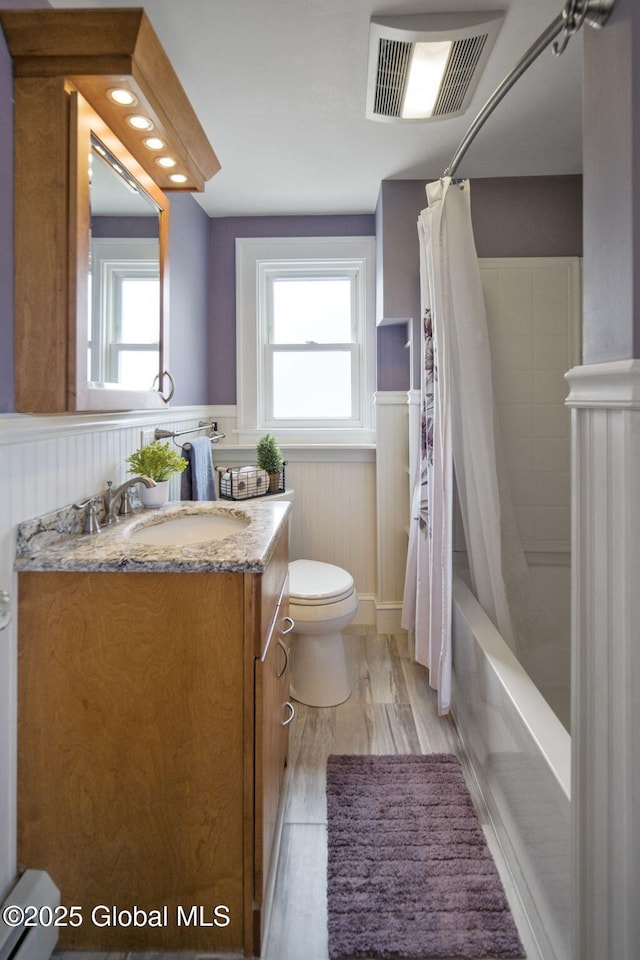 full bathroom featuring wainscoting, toilet, vanity, plenty of natural light, and wood finished floors