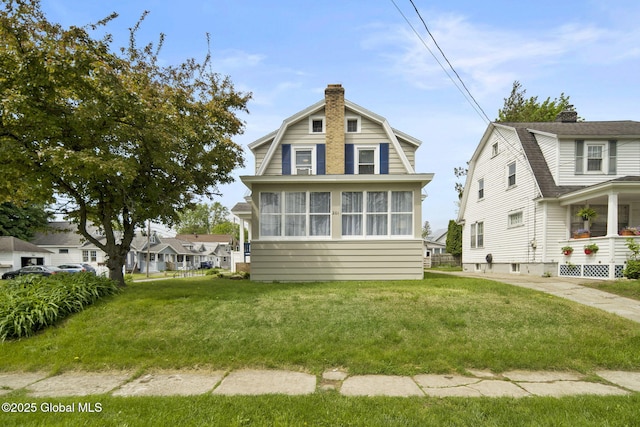 view of front of home with a chimney, a gambrel roof, and a front yard