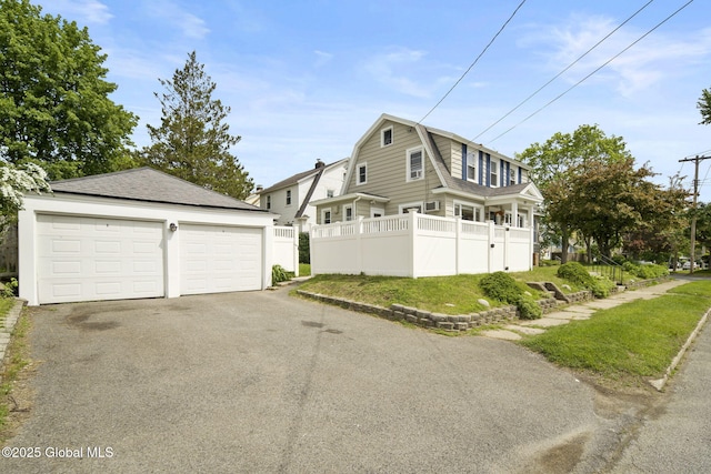 view of front of property with a gambrel roof, an outbuilding, a shingled roof, and a detached garage