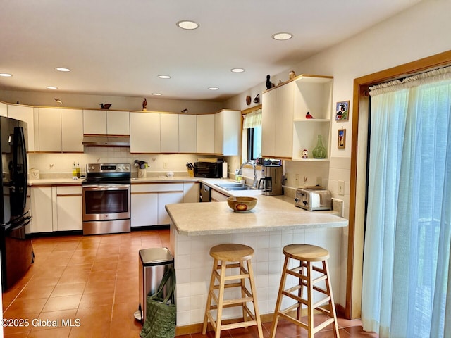 kitchen featuring stainless steel appliances, a peninsula, under cabinet range hood, light countertops, and a sink