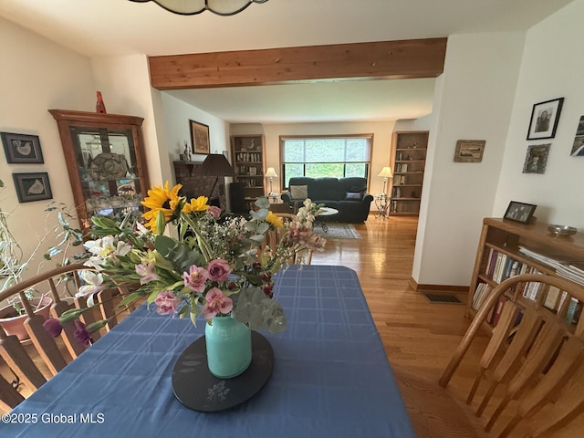 dining room featuring beamed ceiling, wood finished floors, and baseboards