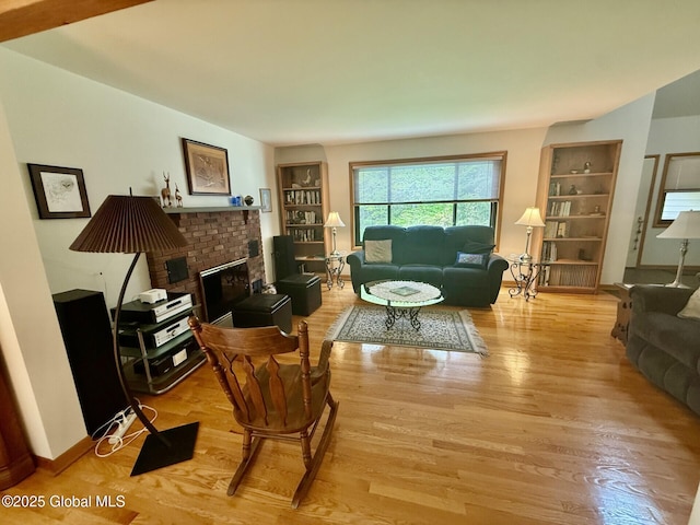 living room with light wood-type flooring, a brick fireplace, and built in features