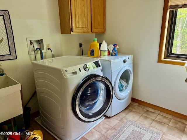 clothes washing area featuring washer and dryer, cabinet space, baseboards, and light tile patterned floors