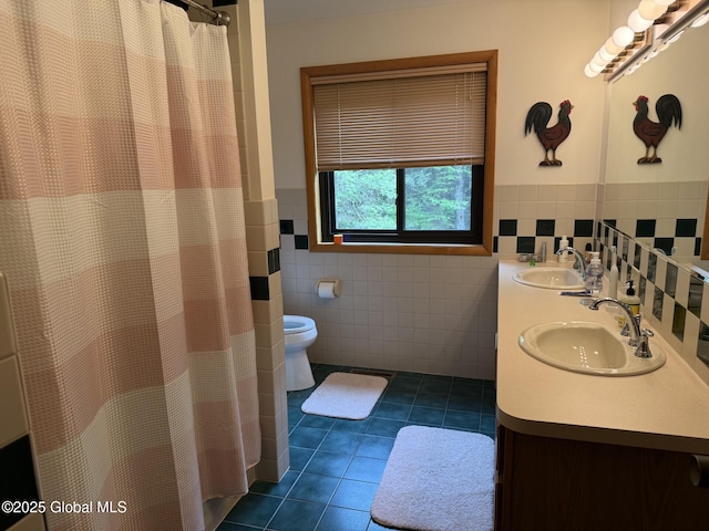 full bathroom with tile patterned flooring, tile walls, toilet, wainscoting, and double vanity