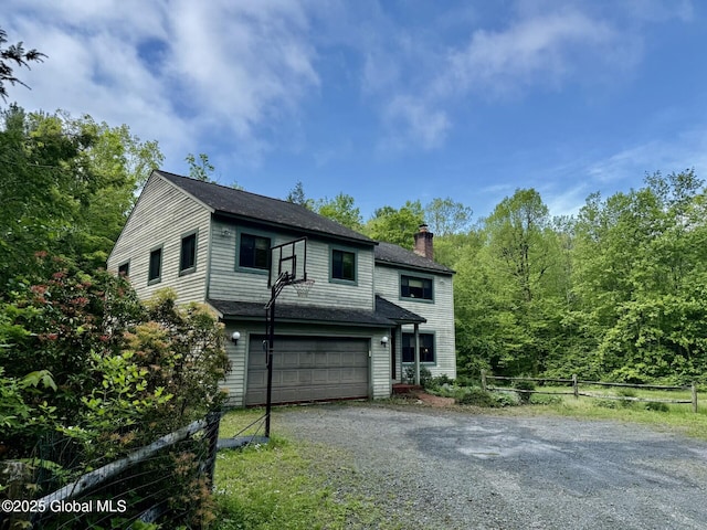 view of front facade with a chimney, driveway, fence, a garage, and roof with shingles
