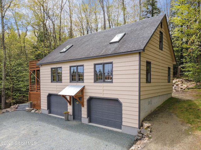 view of front facade featuring a shingled roof, an attached garage, and driveway