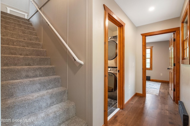 staircase featuring stacked washer and clothes dryer, wood-type flooring, baseboards, baseboard heating, and recessed lighting