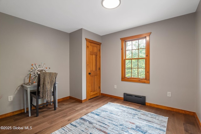 interior space featuring baseboards, wood finished floors, and a baseboard heating unit
