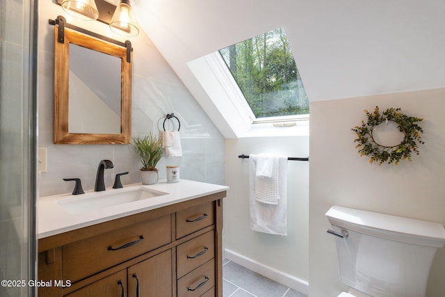 bathroom featuring a skylight, lofted ceiling, vanity, tile patterned flooring, and toilet