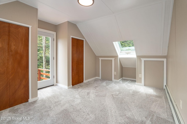 additional living space with baseboard heating, carpet floors, a skylight, vaulted ceiling, and baseboards