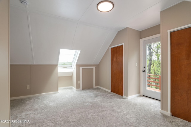 additional living space featuring carpet floors, lofted ceiling, a skylight, and baseboards