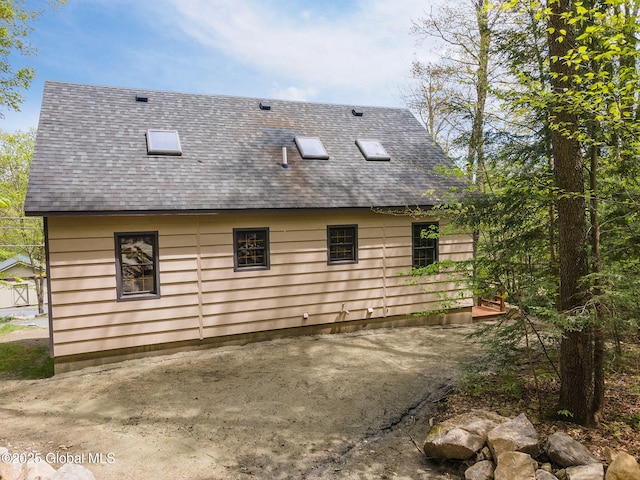 view of side of property with a shingled roof and a patio
