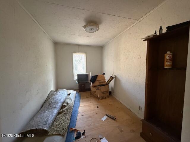 miscellaneous room with a textured wall, a textured ceiling, ornamental molding, and wood finished floors