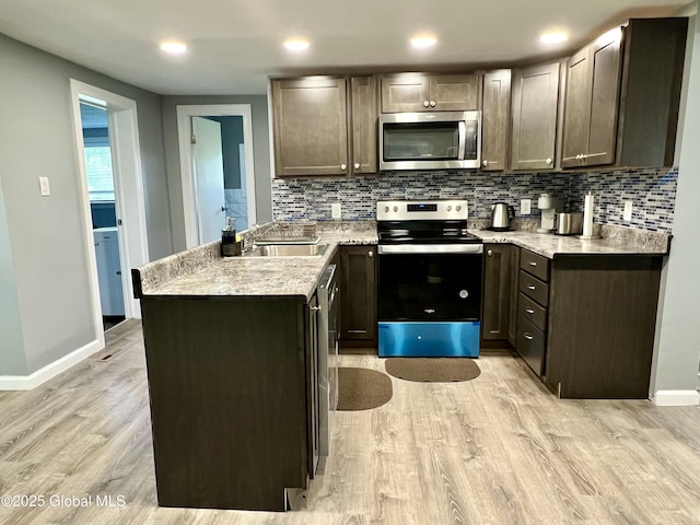 119 Houseman St, Mayfield, NY 12117 - kitchen with stainless steel appliances, a sink, a peninsula, light wood finished floors, and baseboards