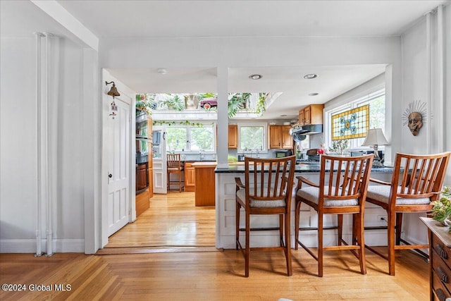 19 George St, Saratoga Springs, Inside, NY 12866 - kitchen featuring brown cabinets, a peninsula, a breakfast bar area, range hood, and dark countertops