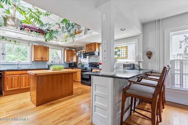 19 George St, Saratoga Springs, Inside, NY 12866 - kitchen with black appliances, under cabinet range hood, a sink, a kitchen bar, and butcher block counters