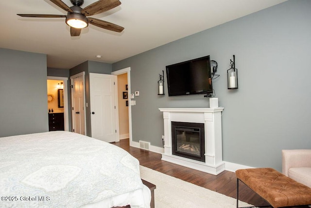 20 Bridgewater Ct, Clifton Park, NY 12065 - bedroom with dark wood-style flooring, baseboards, a glass covered fireplace, connected bathroom, and ceiling fan