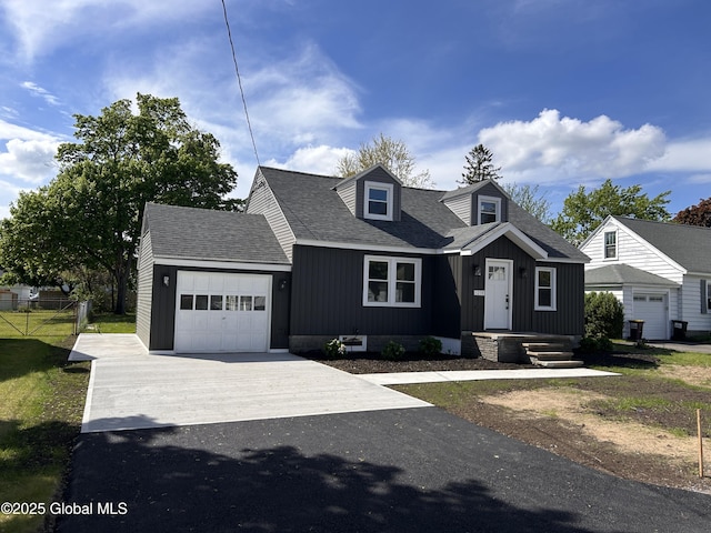 cape cod house with an attached garage, driveway, a shingled roof, and fence