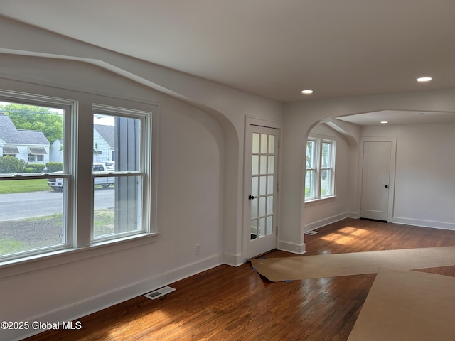foyer entrance with arched walkways, wood finished floors, baseboards, and recessed lighting